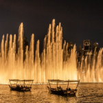 The Dubai Fountain water jets lit up at night with the Burj Khalifa towering behind