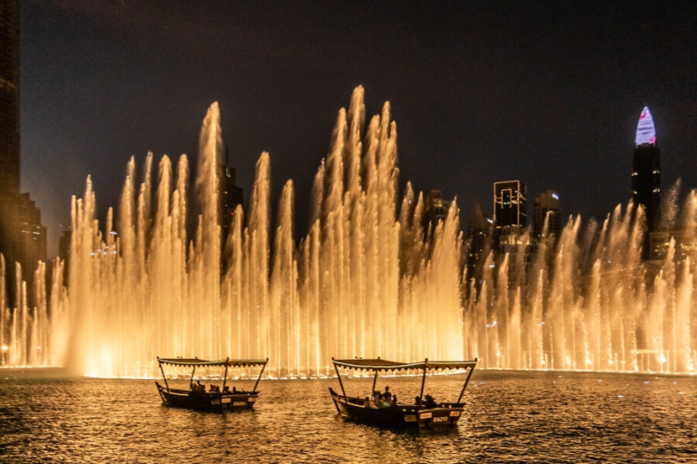 The Dubai Fountain water jets lit up at night with the Burj Khalifa towering behind